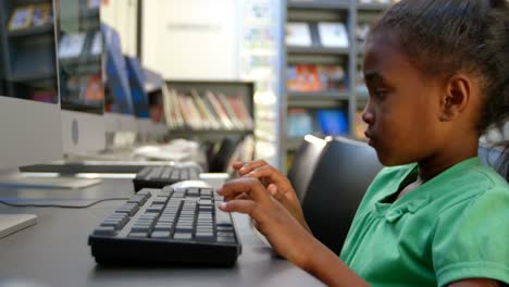 side view of african american schoolgirl using computer in library at school 4k