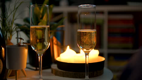 pair of flute glasses filled with bubbly champagne on the table with candlelights