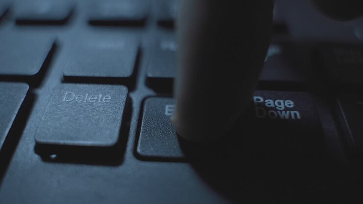 Finger clicking or pressing on End key button on computer keyboard in dark room at night. Coding or hacker pressing to finish task or terminate process. End concept dark web. Delete or remove key