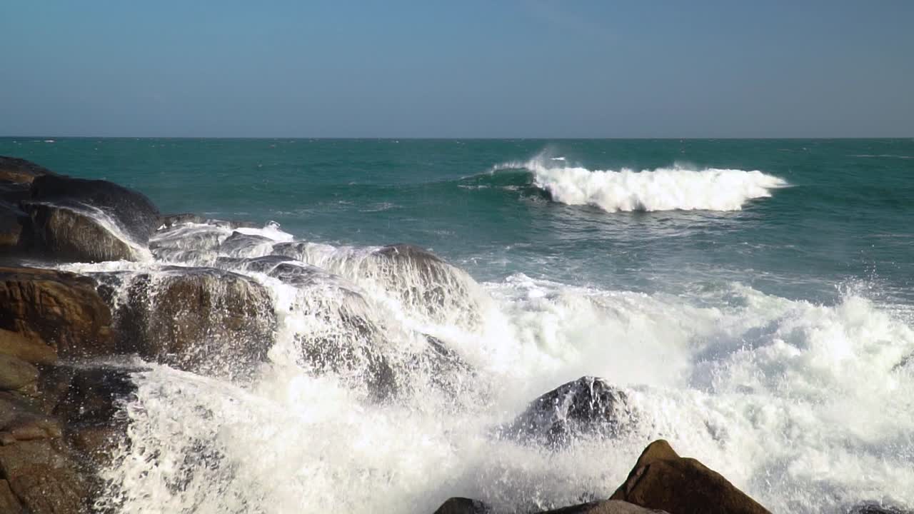 Ocean wave bursting, crashing on dark brown rocks, Hang Rai, Vietnam