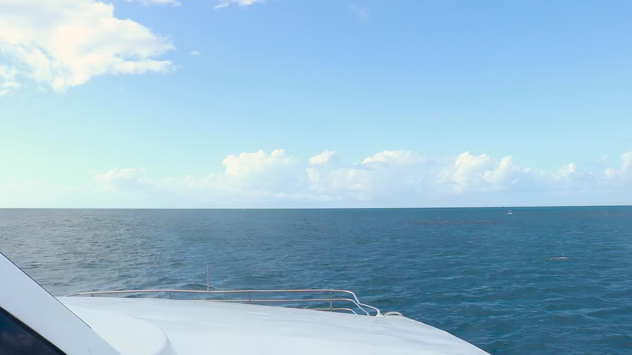 Stern of a white boat with view of the far-reaching, deserted, tropical ocean.