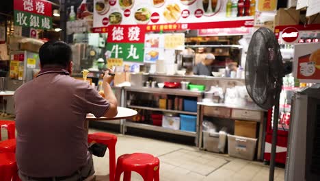 man dining at a bustling street food stall