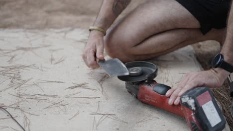 person using an angle grinder to sharpen a blade