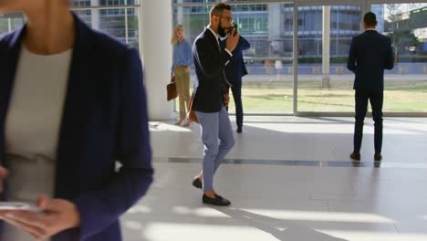 un hombre de negocios de raza mixta llamando por teléfono en el vestíbulo de la oficina 4k