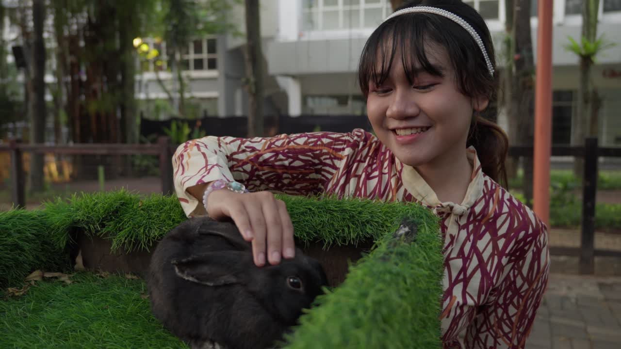Woman Petting a Black Rabbit in a Park