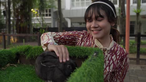 woman petting a black rabbit in a park