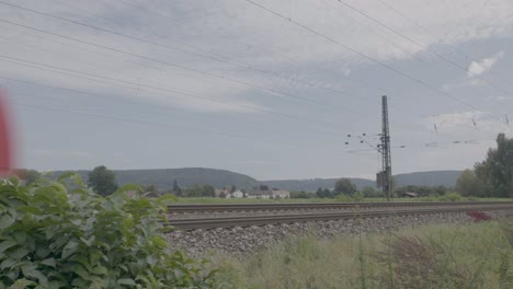 red passenger train in motion, daytime, blurred motion effect, rural landscape backdrop