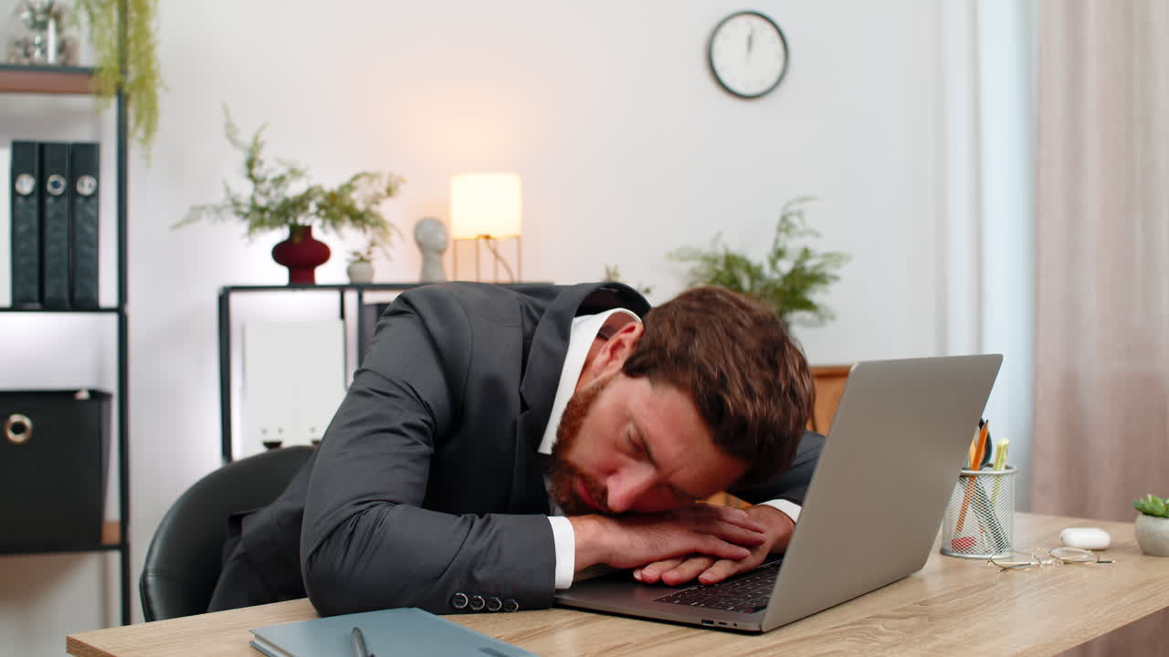 Un uomo d'affari di mezza età esausto digita una relazione e si addormenta sulla tastiera del portatile, a faccia in giù, durante il lavoro