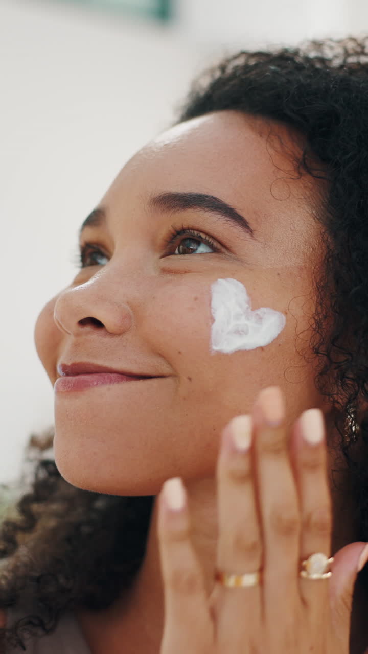 Young Woman Smiling While Applying Cream to Her Face