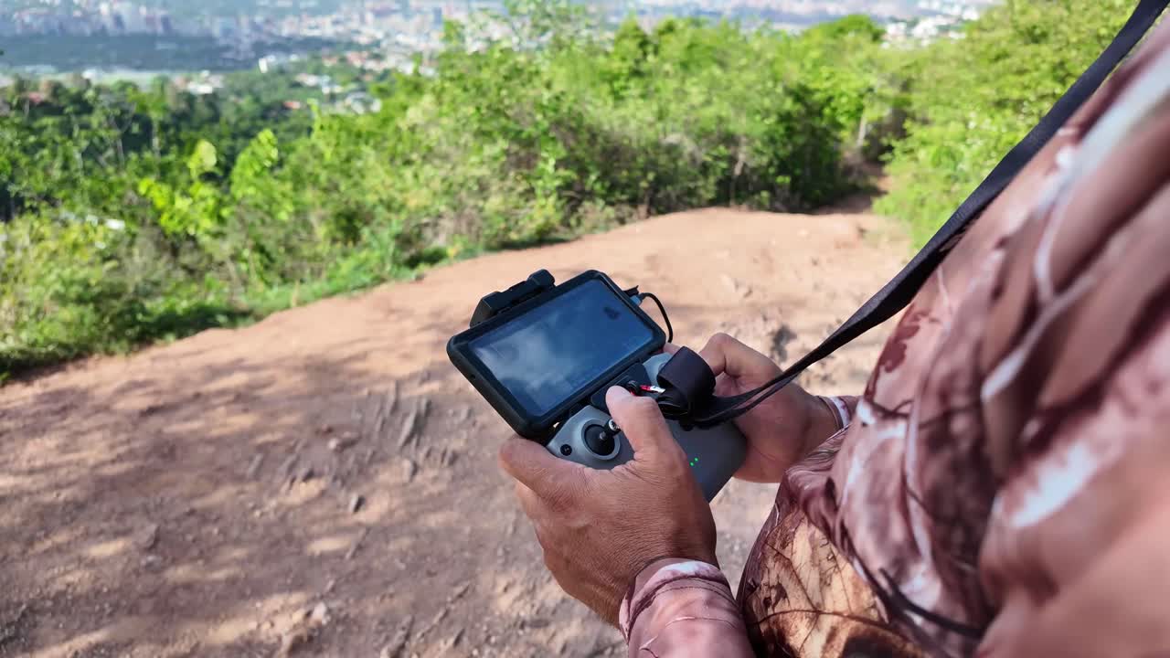 Man flying drone in La Fila with Avila Mountain view, sunny setting