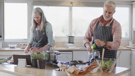 middle aged caucasian couple preparing meal, cooking together in kitchen at home, slow motion