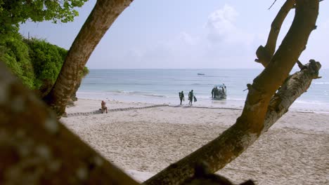 view from distance of couple preparing on scuba diving on vacation in tropical beach of kenya