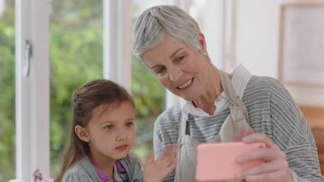 Abuela-Y-Niño-Usando-Un-Teléfono-Inteligente-Teniendo-Video-Chat-Niña-Compartiendo-El-Fin-De-Semana-De-Vacaciones-Con-La-Abuela-Disfrutando-Charlando-Por-Teléfono-Móvil-En-Casa-Con-Su-Nieta