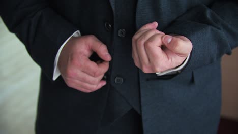 un joven con un tuxedo en el interior muestra un anillo de bodas en su mano