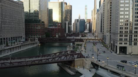 cta train crossing chicago river as drone flies over bridge, low angle