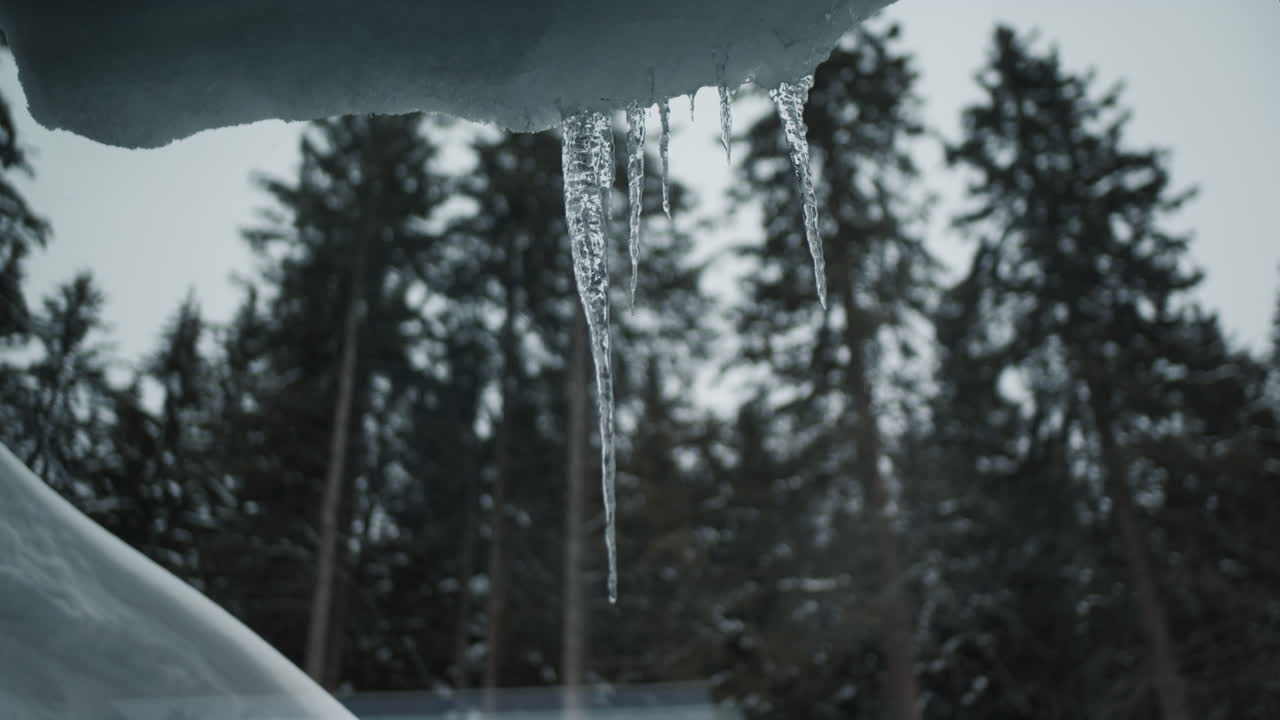 Thaws, melting snow and shiny icicles hanging from roof outside window