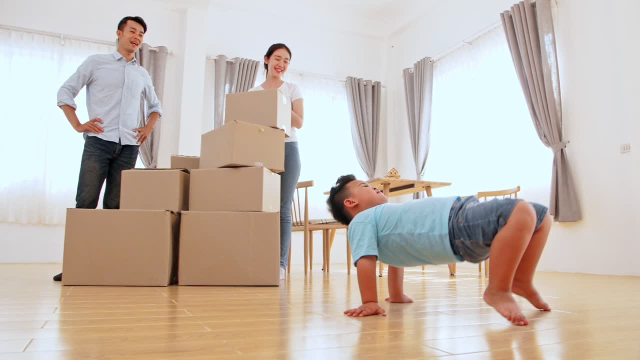Family And Little Boy Dancing In New House At Moving Day
