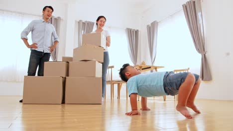 family and little boy dancing in new house at moving day