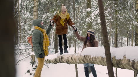 Father-And-Mother-Grab-Their-Daughter's-Hands-As-She-Walks-Along-The-Trunk-Of-A-Tree