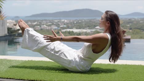 calm tourist practicing yoga in balancing asana poolside against town on coast