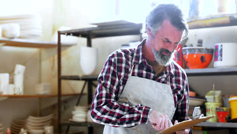 male potter using mobile phone while writing in notepad 4k