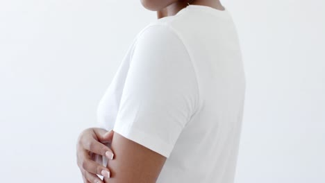 Midsection-of-african-american-woman-wearing-white-t-shirt-with-copy-space-on-white-background