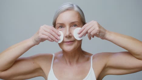 senior woman using cotton pads for facial cleansing