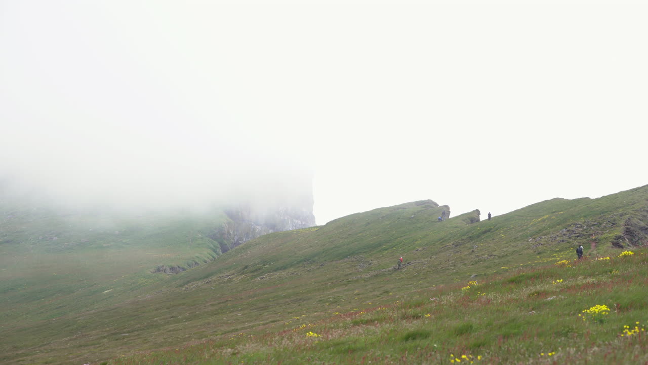 안개가 자욱한 전망, 아이슬란드와 풀이 무성한 절벽에 등산하는 등산객