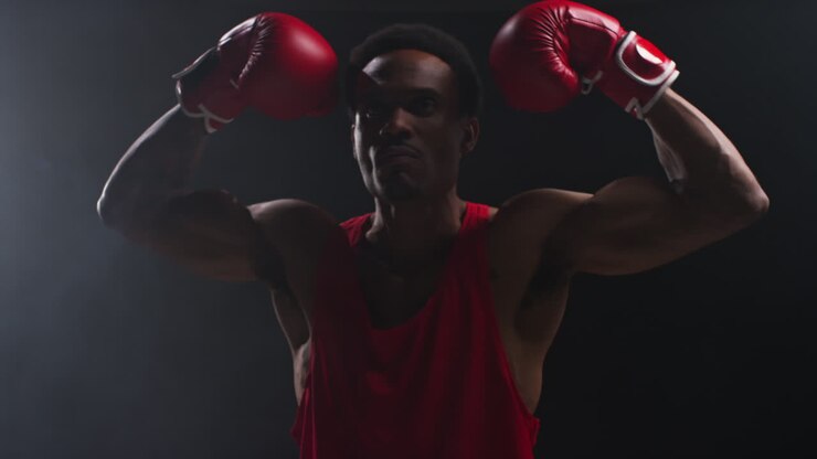Ritratto di un pugile che entra sul ring prima dell'inizio di un incontro di boxe, saluta i fan e si batte il petto con il guantone