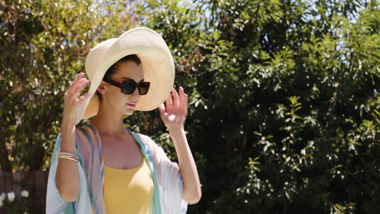 Woman in sunglasses relaxing by poolside on sunny day, smiling brightly