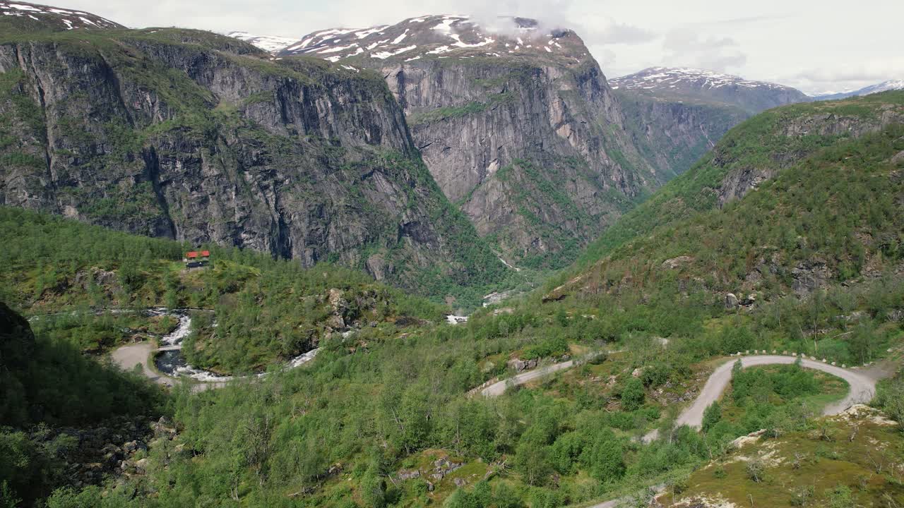 vista aérea de la sinuosa carretera de montaje en el parque nacional de hardangervidda con enormes acantilados en el fondo