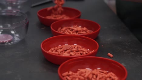 pouring red food granules on red bowls