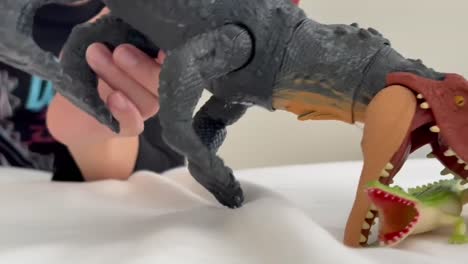 boy playing with a ferocious toy dinosaur action figure that chomps, roars, and thrashes