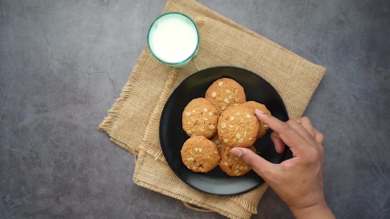 mano alcanzando galletas de avena en un plato con leche