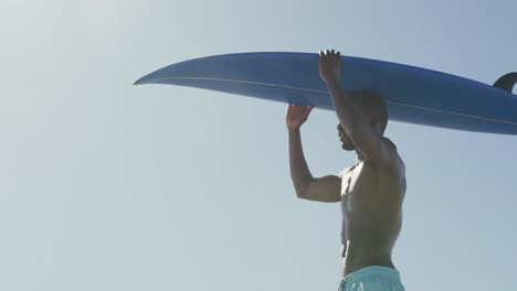 Hombre-Afroamericano-Sosteniendo-Una-Tabla-De-Surf-En-La-Cabeza