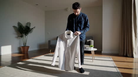 man folding a white shirt at home