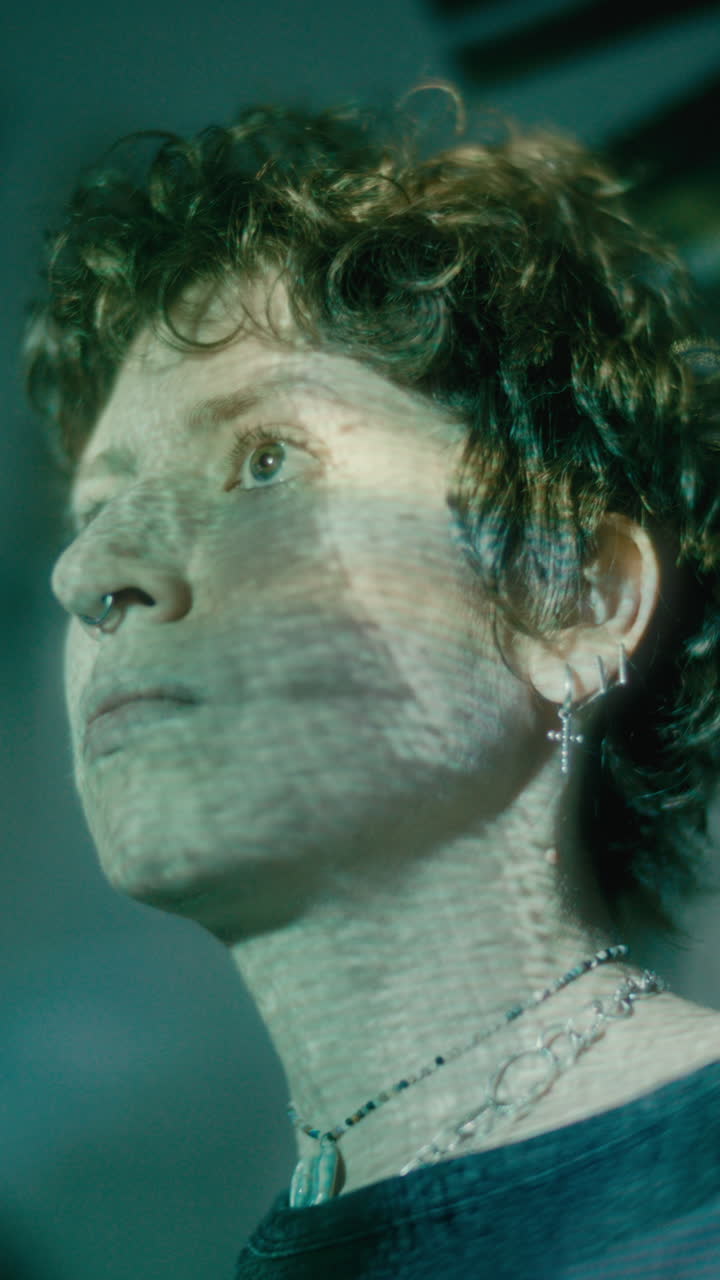 Young Woman Looking Ahead in Dark Room with Light Projections