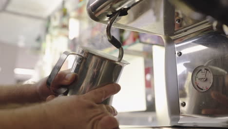 la leche se está vaporizando en un recipiente de acero inoxidable con una máquina de espresso en una cafetería