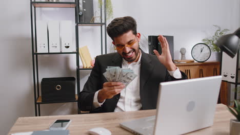 indian businessman winner holding fan of dollar money cash celebrate dance success career salary