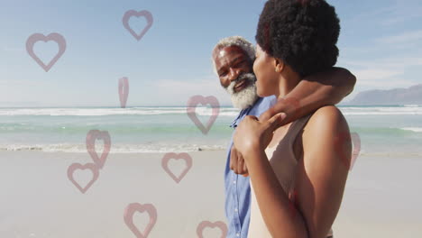 elderly man and young woman walking on beach with heart animation overlay