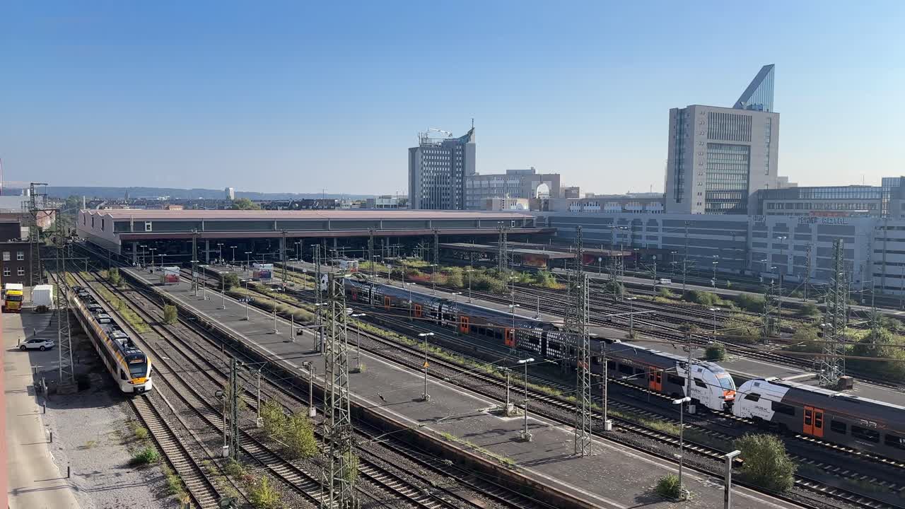 Tren de pasajeros entrando en la principal estación de tren de Düsseldorf con múltiples vías, andenes e infraestructura urbana moderna.