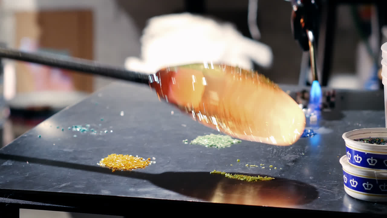 soplador de vidrio que rueda vidrio fundido en piezas de vidrio de color