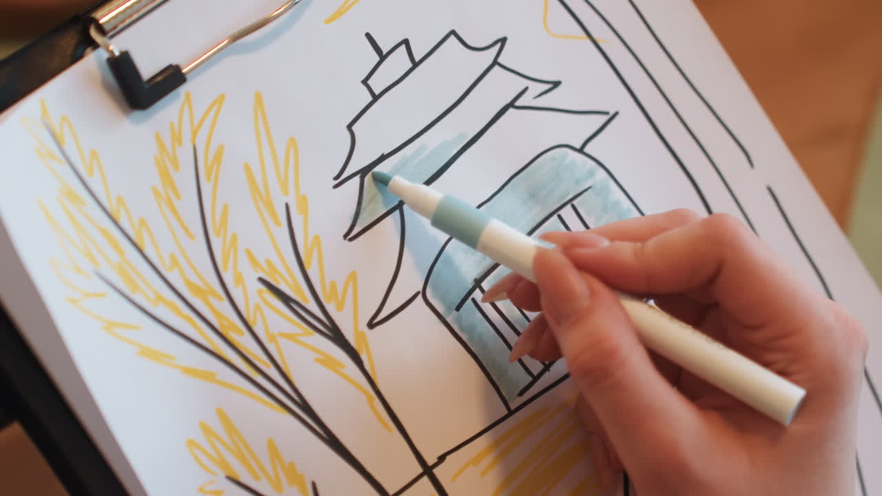 Primo piano di un'artista bianca che colora un tetto a pagoda con un pennarello blu su uno schizzo su clipboard, luce calda dello studio, linee d'inchiostro delicate, disegno di spighe di grano, tratti di mano fermi, atmosfera creativa accogliente, ritmo da tutorial.