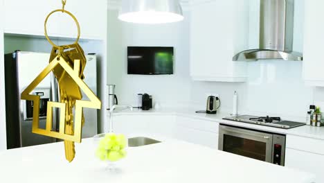 Animation-of-hanging-golden-house-keys-against-interior-of-a-modern-kitchen