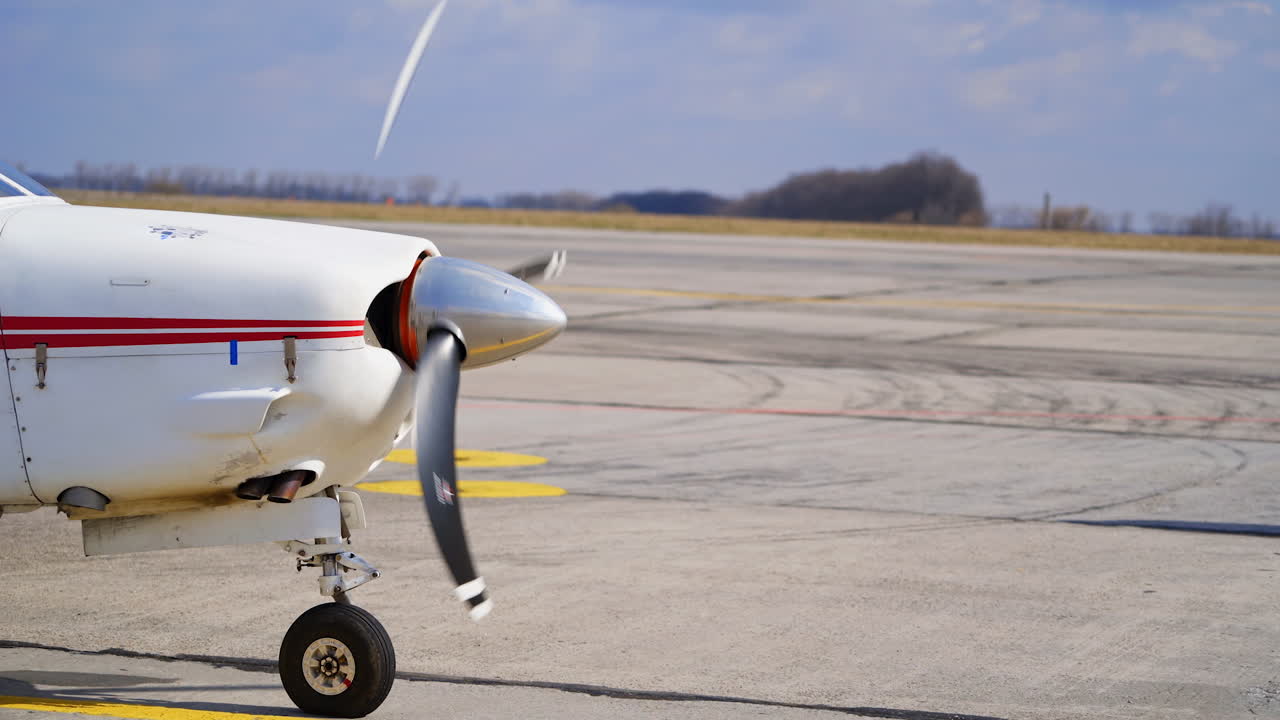 Front part of white aircraft with red lines. Little plane with rotating propeller.