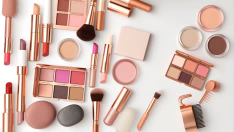 a flat lay of assorted rose gold and pink makeup products and brushes