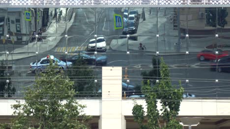 reflection of  traffic in the glass of a modern building