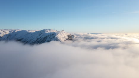 Disparo-De-Dron-Justo-Encima-De-Las-Nubes-De-Inversión-Que-Muestran-Un-Paisaje-Invernal-Con-Montañas-En-Bergen,-Noruega