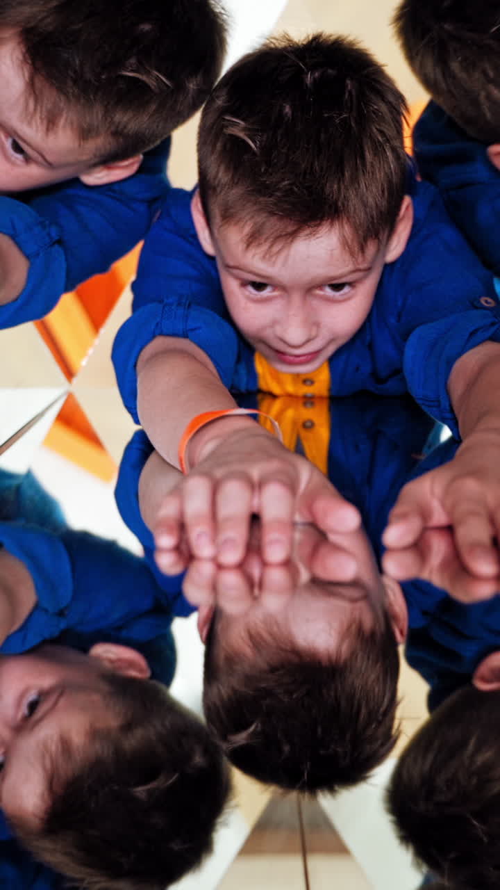 Many small triangles in kaleidoscope and curious boy in each one. Multicoloured pictures of a child in a kaleidoscope tunnel. Vertical video