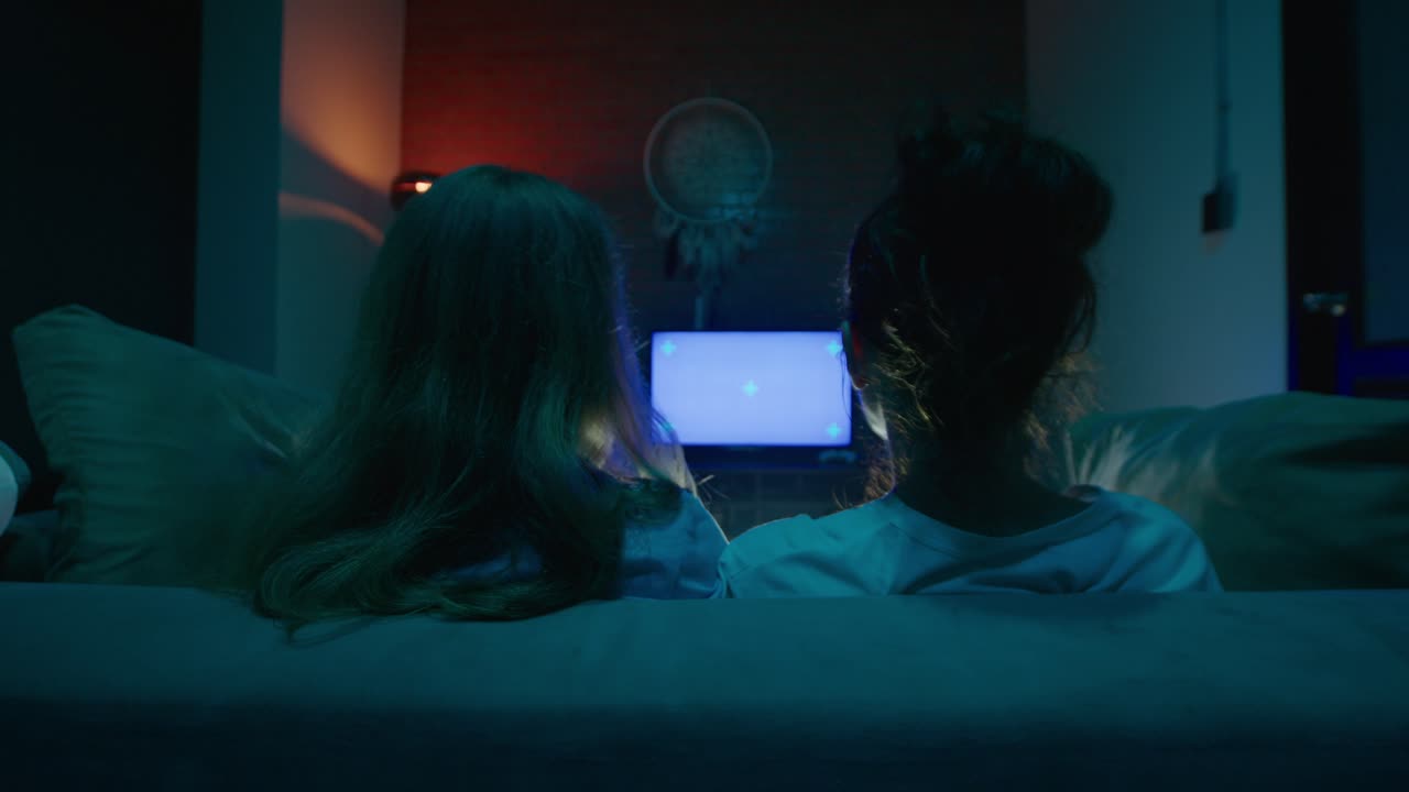Two girls watching TV in their bedroom at night